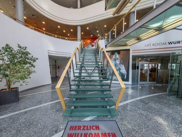 Eingangshalle mit Glasstiege und Fußmatte „Herzlich willkommen“